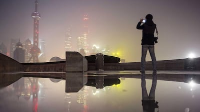 A man uses his mobile phone to take pictures of the financial area of Pudong New District on a smoggy day in Shanghai as heavy smog and thick fog engulfed many parts of northern and eastern China on November 30, 2015. Reuters