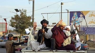 Taliban fighters wave from the back of a pickup truck, in Kabul, Afghanistan, on August 30, 2021. AP