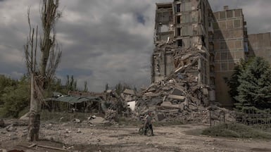 A resident pushes a bicycle past a destroyed building after shelling in Toretsk, eastern Donetsk. AFP