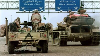 A US Humvee jeep and a Saudi tank pass under a highway sign directing them to Kuwait City, February 26, 1991 during Desert Storm Allied forces offensive. AFP