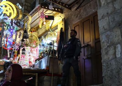 A member of the Israeli security forces stands guard at one of Al Aqsa mosque entrance in the old city of Jerusalem, as a shops sell ornaments ahead of the Muslim holy month of Ramadan, March 31,2022. AFP