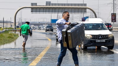 A man carries his luggage through floodwater caused by heavy rain on Sheikh Zayed Road in Dubai, in April 2024. AP