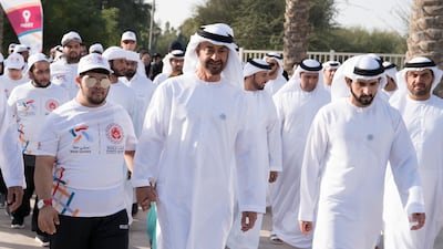 Sheikh Mohamed walks hand in hand with an Emirati Special Olympic athlete.