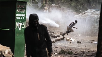 A protester takes cover from the jet of a water cannon during clashes with police forces in Kibera, Nairobi. Marco Longari / AFP Photo