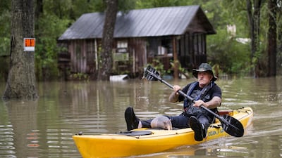 Donnie McCulley paddles out from a flooded neighborhood caused by heavy rain spawned by Tropical Depression Imelda with an armadillo as a passenger. AP