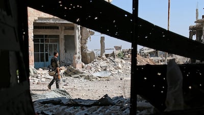 A Free Syrian Army fighter carries his weapon as he walks past damaged buildings in a rebel-held part of Deraa city in Syria's south-west on July 9, 2017. Alaa Al Faqir / Reuters