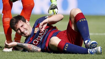 Barcelona's Lionel Messi grimaces as he lies on the pitch after injuring his left knee during their Spanish first division soccer match against Las Palmas at Camp Nou stadium in Barcelona, Spain, September 26, 2015. REUTERS/Sergio Perez