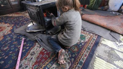 An internally displaced girl, who fled from western Aleppo countryside, sits next to a heater inside a tent in Afrin, Syria. REUTERS