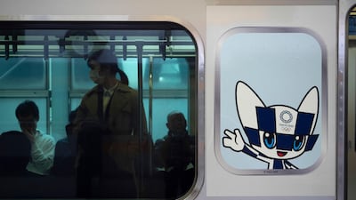 Commuters in a train carrying a poster showing the Tokyo 2020 Olympics mascot, Miraitowa, in Tokyo. AP