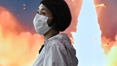 A woman walks past a screen at a railway station in Seoul which shows footage of a North Korean missile test. AFP