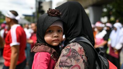 A mother carries her daughter during a rally organised by Muslim politicians against the signing of the UN anti-discrimination convention (ICERD) at Merdeka Square in Kuala Lumpur. AFP