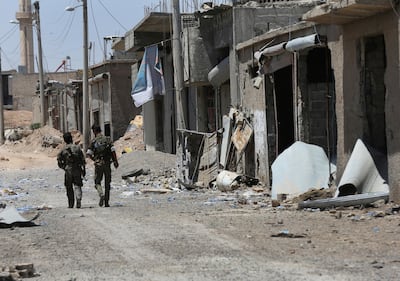 Syrian Democratic Forces fighters walking past destroyed shops on the front line of the industrial district on the eastern side of Raqqa, Syria, on July 26, 2017. Hussein Malla/AP Photo