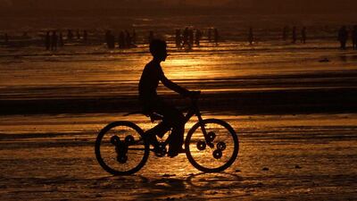 A boy is silhouetted against the setting sun as he rides a bicycle at Karachi's Clifton beach. Athar Hussain / Reuters