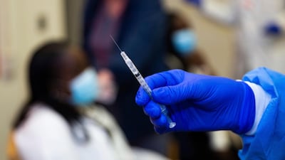 A doctor prepares to administer a vaccine injection. AP