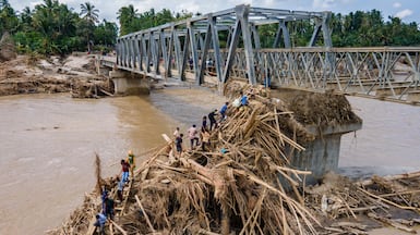 Residents walk over debris to cross the river on a newly built bridge connecting Aceh and North Sumatra province, which was damaged by flash floods, in Bireuen district, Indonesia. AFP