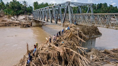 Residents walk over debris to cross the river on a newly built bridge connecting Aceh and North Sumatra province, which was damaged by flash floods, in Bireuen district, Indonesia. AFP