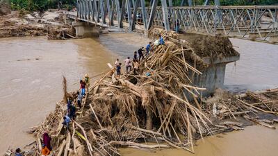 Residents walk over debris to cross the river on a newly built bridge connecting Aceh and North Sumatra province, which was damaged by flash floods, in Bireuen district, Indonesia. AFP