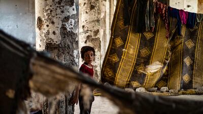 A Syrian boy, displaced with his family from Deir Ezzor, looks at the camera inside the damaged building where he is living in Syria's northern city of Raqqa.