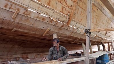A shipbuilder works on a dhow at the boatyard.