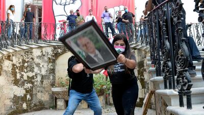 Protesters take down a picture of Lebanese President Michel Aoun as they enter the foreign ministry headquarters during a protest in Beirut, Lebanon. EPA
