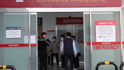 Cleaning workers in uniforms wear face masks next to a notice on preventing infection at a hospital, where a Chinese woman who was confirmed to have the new coronavirus strain is isolated, in Incheon. AFP