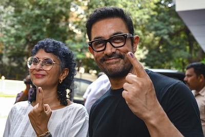 Bollywood actor Aamir Khan and director Kiran Rao, left, hold up their ink-marked fingers after voting in Mumbai. AFP