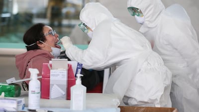 Medical workers wearing protective gear take samples from a foreign visitor at an 'Open Walking-Thru' centre for coronavirus Covid-19 tests at the airport in Incheon. EPA