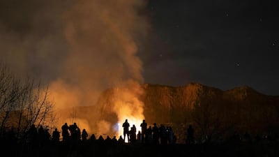 People watch the scene of a gorse fire below Salisbury Crags in Holyrood Park, Edinburgh, Scotland. AP