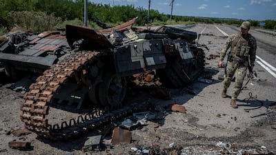 A Ukrainian serviceman walks near a destroyed Ukrainian tank, as Russia's attack on Ukraine continues
