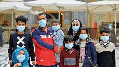 Members of an Iraqi family, all wearing masks, pose for a picture during their visit to the shrine of Imam Ali in the holy Iraqi central city of Najaf. AFP