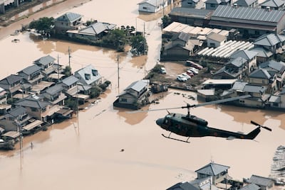 A helicopter flies over a flooded housing area in Kurashiki, Okayama prefecture, western Japan Monday, July 9, 2018. People prepared for risky search and cleanup efforts in southwestern Japan on Monday, where several days of heavy rainfall had set off flooding and landslides in a widespread area. Kyodo News via AP