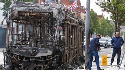 People clean the street next to a burnt-out bus. AFP