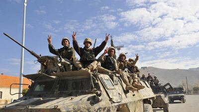Lebanese soldiers gesture while riding on an armoured vehicle as they leave the mountainous border town of Ras Baalbek (REUTERS/Hassan Abdallah)