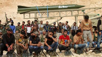 Syrian rebel fighters sit behind deployed machine guns during a military parade near the southern city of Deraa on June 7, 2018, with a surface-to-surface missile in the background. Mohamad Abazeed / AFP