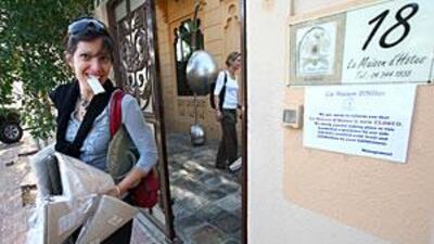 A shopper leaves La Maison d'Hôtes with items sold at a discount by the hotel, now closed.