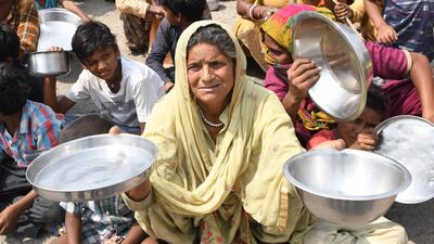 Families from Maharashtra hold out utensils to protest the lack of food in a slum area on the outskirts of Amritsar, Punjab, May 31. Narinder Nanu / AFP