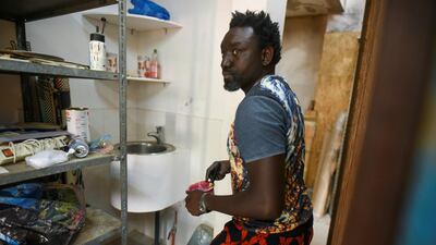 Senegalese artist Omar Ba mixes paint in a plastic cup in a storage area of his studio. Cooper Inveen / Reuters