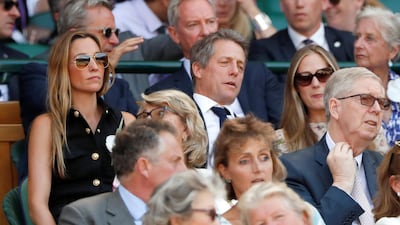 Hugh Grant and Anna Eberstein sit in the Royal Box ahead of the men's singles final. Reuters