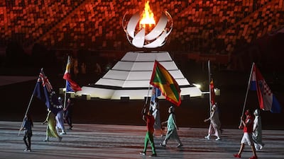 Athletes carrying nations' flags walk past the Olympic flame as they enter the stadium during the closing ceremony.
