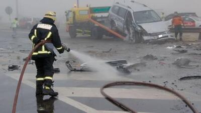 A fire fighter cleans up after an 18-car pile-up in heavy fog on the Tarrif-Abu Dhabi road.