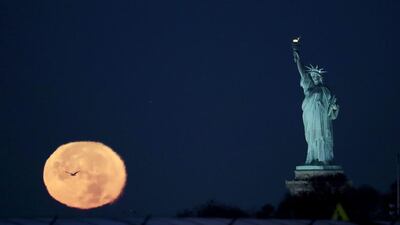 The supermoon appears near the Statue of Liberty in New York City. Julio Cortez / AP Photo