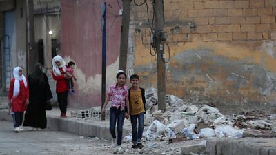 People walk past rubble in the border town of Tal Abyad, Syria, October 16, 2019. REUTERS/Khalil Ashawi