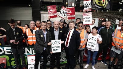 General secretary of the Rail, Maritime and Transport union Mick Lynch, centre, with striking workers at London Euston train station. PA