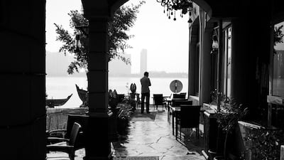 A lone man waits for customers to arrive in a breakwater cafe across from the Abu Dhabi Corniche. Brian Kerrigan / The National