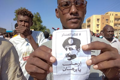A Sudanese protester holds a poster depicting coup leader Gen Abdel Fattah Al Burhan, which reads "No to Military Rule!" and "Burhan, leave!". AFP