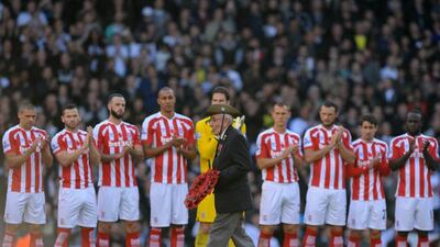 A former soilder lays a wreath of poppies while Stoke City players line up for a moment of silence in a mark of respect to fallen soilders since World War I on Remembrance Day before their Premier League match with Tottenham on Sunday. Olly Greenwood / AFP