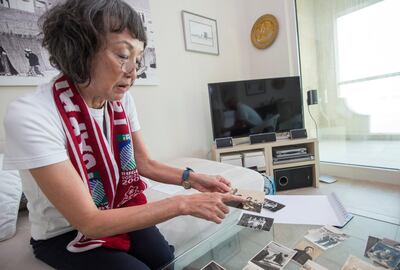Kimi Makashima, a long-term UAE residen from Japan, looking through old photos of rugby games at her apartment in Dubai. Leslie Pableo for The National