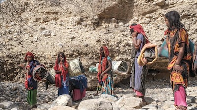 Internally displaced woman carry blankets in the makeshift camp. AFP