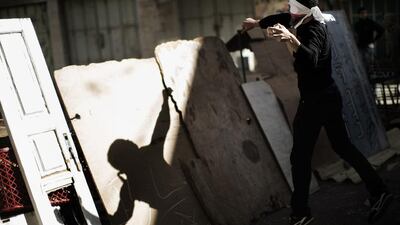 A Palestinian throws stones towards Israeli soldiers during clashes in the West Bank city of Hebron. Marco Longari / AFP Photo