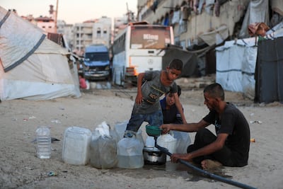 Displaced Palestinians fill containers with water at a tent camp in Gaza city. Reuters